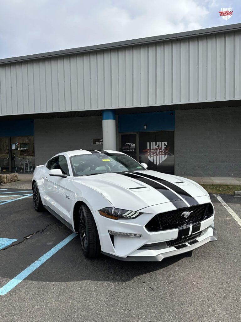 a white sports car with black stripes parked in a parking lot