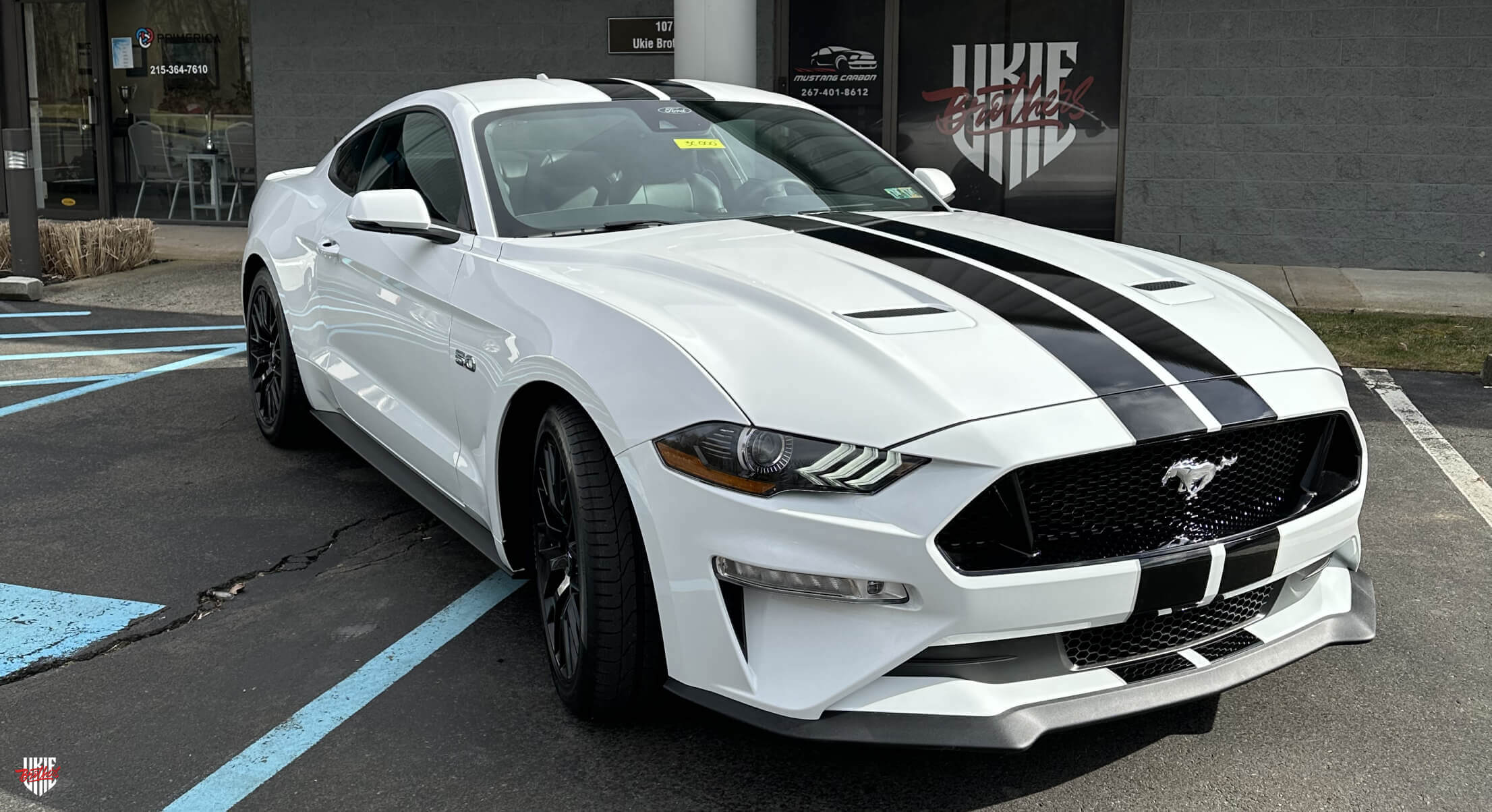 White Ford Mustang with a custom vinyl wrap by Ukie Brothers, showcasing a sleek and modern design, parked outdoors.